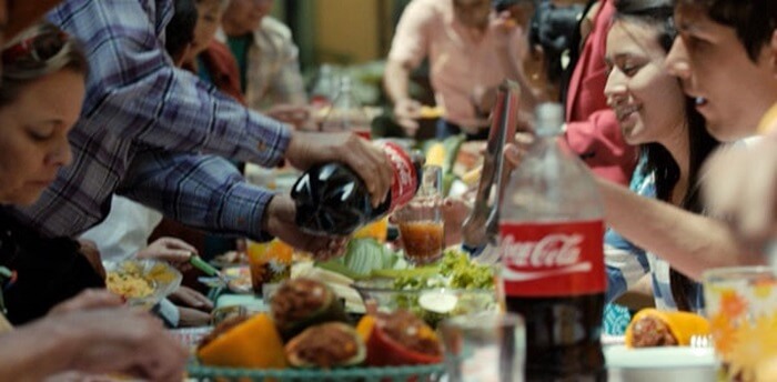 Pessoas confraternizando com uma garrafa de Coca-Cola em destaque